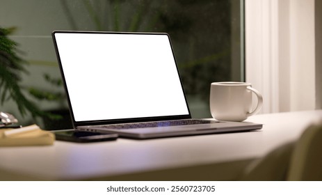 Espaço de trabalho configurado com um laptop e uma caneca de café, perto de uma janela com uma vista discreta para a vegetação, perfeito para noites produtivas.