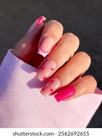 Une jeune fille avec des ongles carrés roses et des motifs de cœurs pour la Saint-Valentin. Manucure Saint-Valentin. Ongles aux tons pastel. Ongles en forme de cœur. Jolie manucure. Fête