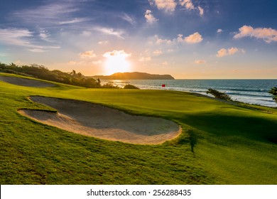 Búnkers de arena en el hermoso campo de golf al lado del océano al atardecer, hora del amanecer.