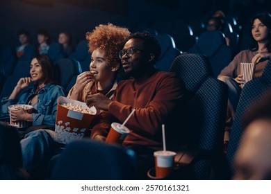 Young happy couple enjoying during film screening at movie theatre.