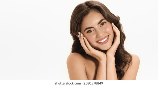 Romantic photo of a beautiful woman with curly hair, flowing skin and white smile. Female model with flawless face, radiant shine after skincare routine, posing over white studio background,