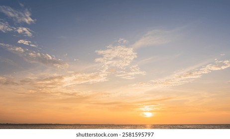 Oranje zonsondergang met wolken boven de zee in de avond, verlicht door geel zonlicht. De horizon, de zee en de hemel vormen een landschap op de achtergrond, met de zonsondergang tijdens het gouden uur in de zomer. De schemering begint.