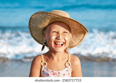 Vacanze per bambini al mare. Crema solare per bambini. Bambina abbronzata e felice con la crema solare sul viso che si diverte sullo sfondo del mare.