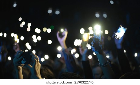 Birçok eğlenceli insan ellerini kaldırıp cep telefonlarının flaşını tutuyor. Hayran kalabalığı el fenerlerini sallıyor. Muhteşem canlı müzik konseri atmosferi. Büyük açık hava K-pop arenası. Harika gece festivali. Çok sayıda neşeli adam takılıyor. K-pop rahatlığı.