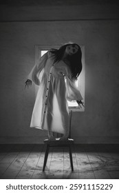 Figura soprannaturale, donna con lunghi capelli scuri che le coprono il viso, in abito bianco, in piedi su una sedia in una stanza vuota e inquietante, immagine monocromatica. Concetto di mistero, fantasy. Copertina di un film horror.