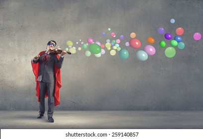 Young man in superhero costume playing violin