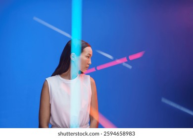 Portret mlade žene koja gleda desno u obojena neonska svjetla. Žensko lice azijske djevojke na živopisnoj pozadini modnog studija. Kul osoba u reklami za urbani način života ili visokotehnološki život.