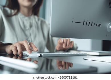 Mulher de negócios trabalhando em um computador de mesa, clicando com o mouse em um tablet digital sobre a mesa do escritório. Empresária trabalhando online, navegando na internet em seu escritório em casa, trabalho remoto, close-up.