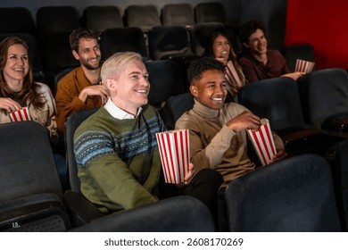 Raznolika grupa prijatelja smiju se i jedu kokice dok gledaju film u kinu