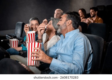 Grupe prijatelja smiju se i uživaju u kokicama dok gledaju uzbudljiv film u ugodnoj kino dvorani, dijeleći trenutke radosti zajedno