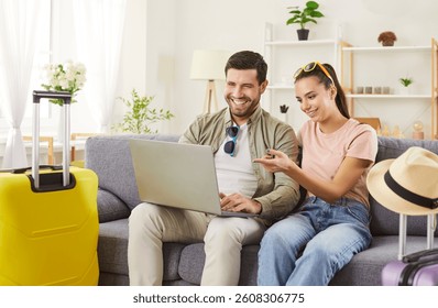 Pasangan turis bahagia menggunakan laptop online, orang-orang bahagia di rumah saat musim panas, tas koper untuk bepergian, merencanakan perjalanan liburan, koper kuning besar, mimpi bulan madu, mengenakan pakaian pantai liburan, menikmati.