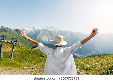 Vista panoramica posteriore di una giovane donna adulta con una maglietta bianca che alza le mani e si gode l'esplorazione del paesaggio alpino austriaco con vista sul caldo tramonto soleggiato. Donna felice che esplora le Alpi, la cima del Großglockner.