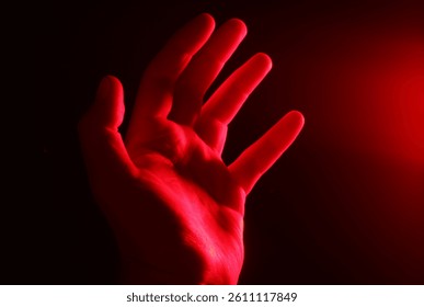 Mano maschile illuminata da una luce al neon rossa