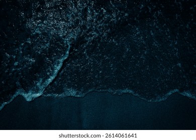 Aussicht von oben auf den dunklen Sandstrand
