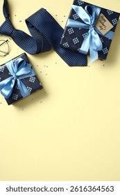 Vatertags-Illustration mit flach liegenden Geschenken, Krawatte und Brille, die oben auf gelbem Hintergrund mit Konfetti angeordnet sind. Draufsicht mit Platz für Text.