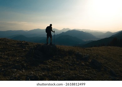 Uomo che scala la cima di una montagna. Vista posteriore di uno scalatore che ammira il successo. Successo e avventura.