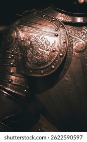 Detalhe ampliado de uma armadura medieval ornamentada com padrões gravados.