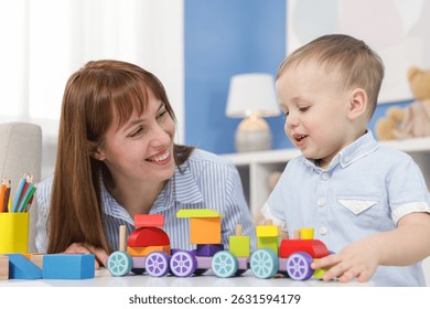 แม่และลูกชายกำลังเล่นของเล่นที่โต๊ะในบ้าน