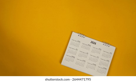 Kalendářní plán pro rok 2026 na žlutém podkladu. Kalendář 2026, plánování schůzek, koncept. Kopírovat prostor. Pohled shora.