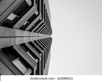 Abstrakt udsigt ser op på moderne beton- og glasbygning. Kunstnerisk syn på udvendig arkitektonisk design og detaljer. En moderne kontorbygning med abstrakt farvebaggrund.