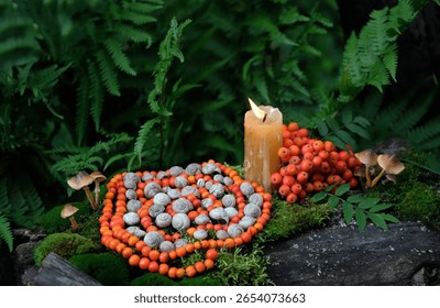Bougie et spirale faites de coquilles d'escargots et de baies de sorbier en forêt. Sorcellerie, pratique protectrice du sorbier. Rituel ésotérique spirituel wiccan pour la fête de Mabon. Mandala de la nature pour la magie verte