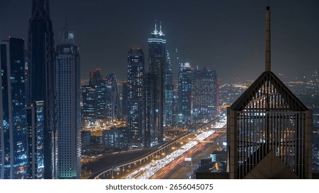 Modern skyscrapers and busy evening highways night timelapse in luxury downtown of Dubai city. Top aerial view from tower rooftop. Dubai, United Arab Emirates