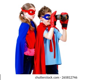 Djalë dhe vajza adoleshentë me një kostum superheronjsh që shikojnë me dylbi. I izoluar mbi sfond të bardhë.