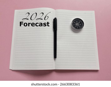 Previziuni de piață pentru anul 2026 pe un caiet. Așteptări pentru anul 2026. O busolă și un stilou negru pe fundal roz de masă.