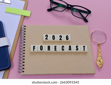 Previziuni pentru anul 2025 pe un caiet maro ca fundal pentru notele de predicții de piață. Conceptul de așteptări pentru anul 2026. Ochelari, lupă și caiet.