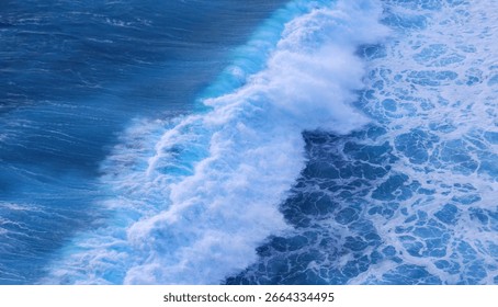 Meereslandschaft mit dunklem Ozeanhintergrund, Wellen spritzen gegen Felsen. Tropischer Strand im Sommer, draußen am Meer. Blaues Wellenmuster auf der Wasseroberfläche. Türkisfarbenes Meerwasser, weiße Wellen spritzen tiefblaues Meer