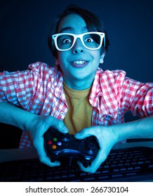 Le gusta jugar y ganar videojuegos. En la luz azul del monitor, el niño emocional juega juegos de computadora en línea.