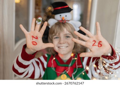 Concentrez-vous sur les paumes d'un enfant joyeux, portant les chiffres de la nouvelle année 2026. Douceur et amusement à la maison pour la veille de Noël. Faire un vœu.