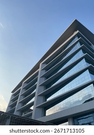 Contemporary high-rise building captured from below, showcasing sleek lines, mirrored glass panels, and modern architecture. The photo symbolizes corporate growth, business districts, and the dynamic