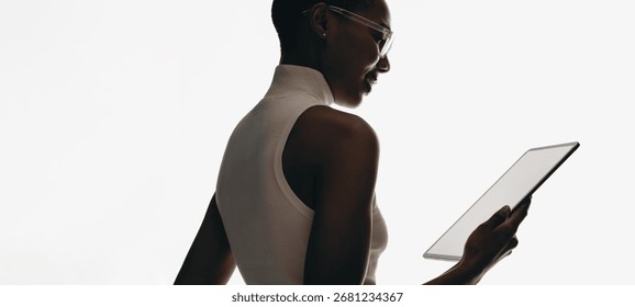 Profil d'une femme active tenant une tablette moderne à écran vierge, sur fond blanc. Idéal pour les maquettes technologiques, les présentations créatives et les concepts minimalistes d'entreprise.