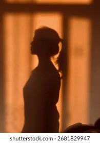Künstlerischer Schatten eines Mädchens auf dem Boden, der eine deutliche Silhouette bildet. Minimalistische Komposition, die menschliche Form, Licht und Kontrast in einem einfachen, aber ausdrucksstarken Bild hervorhebt.