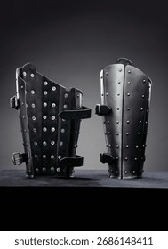 Manoplas de armadura medieval de aço com rebites em superfície preta.