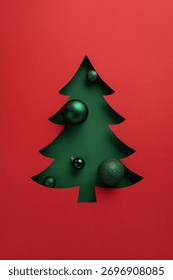 Un sapin de Noël minimaliste vert, orné de décorations brillantes sur un fond rouge vif, crée une ambiance festive. Idéal pour Noël, le Nouvel An et les campagnes de cadeaux de fin d'année.