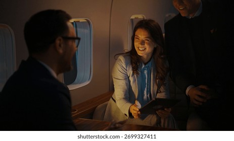 Des collègues de travail se réunissent à bord d'un jet privé, riant et discutant tout en consultant des informations sur une tablette, illustrant ainsi le luxe des voyages et la productivité professionnelle.
