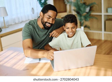 Un père et son fils font leurs devoirs sur un ordinateur portable à la maison. Un père et son fils adolescent utilisent un ordinateur portable. Un garçon et son père sont assis à la maison et travaillent avec un cahier.