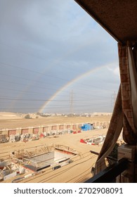 Esta fotografia impressionante captura um momento raro e cativante em que um vibrante arco-íris duplo se estende por um céu dramático e repleto de nuvens. O amplo arco de cores domina a porção superior.