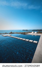Piscine à débordement de luxe surplombant l'océan sous un ciel bleu azur