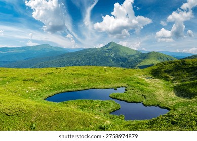 Landskap musim panas dengan tasik gunung kecil, bukit berumput hijau dan langit biru dengan awan gebu. Pergunungan Carpathian