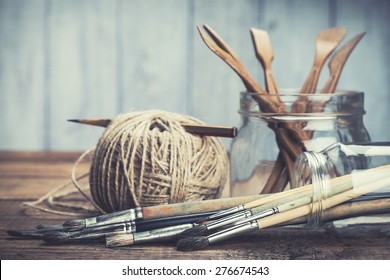 Strumenti per arte e artigianato. Pennelli da artista, set per scultura e matita in barattoli di vetro su sfondo rustico. Messa a fuoco selettiva.