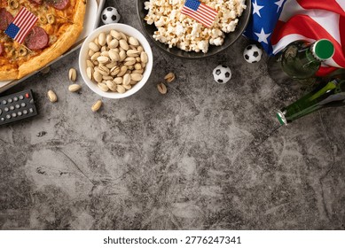 Zestaw do oglądania meczów piłkarskich z flagą USA, pizzą, popcornem, pistacjami, butelkami piwa i pilotem, sugerujący świętowanie meczu