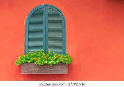 オレンジ色の壁と色とりどりの花と緑の木製窓