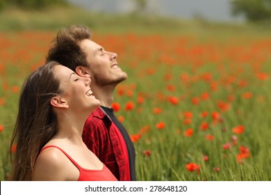 Pareja feliz respirando aire fresco en un campo colorido con flores de amapola roja