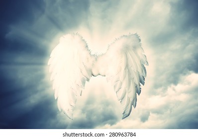 ガーディアン エンジェルの白い翼は、光のあるドラマチックなグレーの上にあります。宗教と精神的な概念
