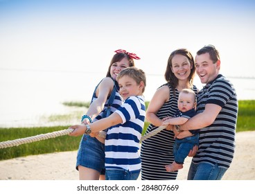 Tovtrækning - familie leger på stranden. Sommerferie og familiekraftkoncept