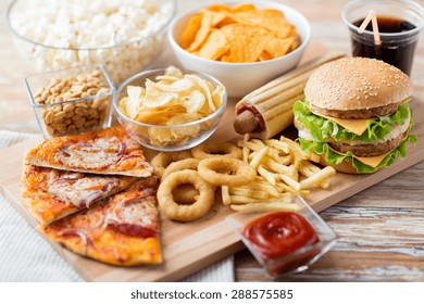 fast food and unhealthy eating concept - close up of fast food snacks and cola drink on wooden table
