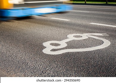 Znak za električni avtomobil na cesti z javnim prevozom v ozadju.
